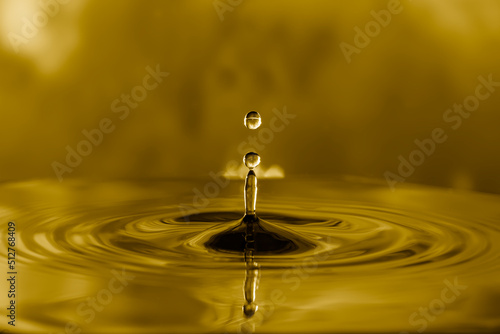 Water droplets on water surface to create ripples on golden light effects background.