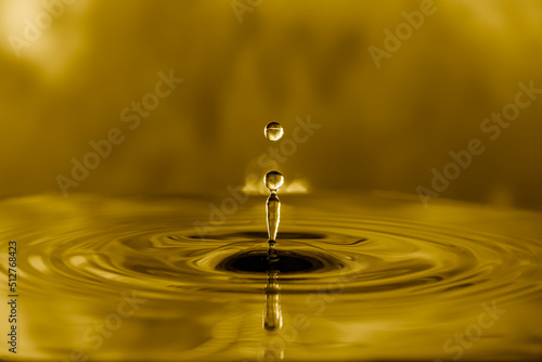 Water droplets on water surface to create ripples on golden light effects background.