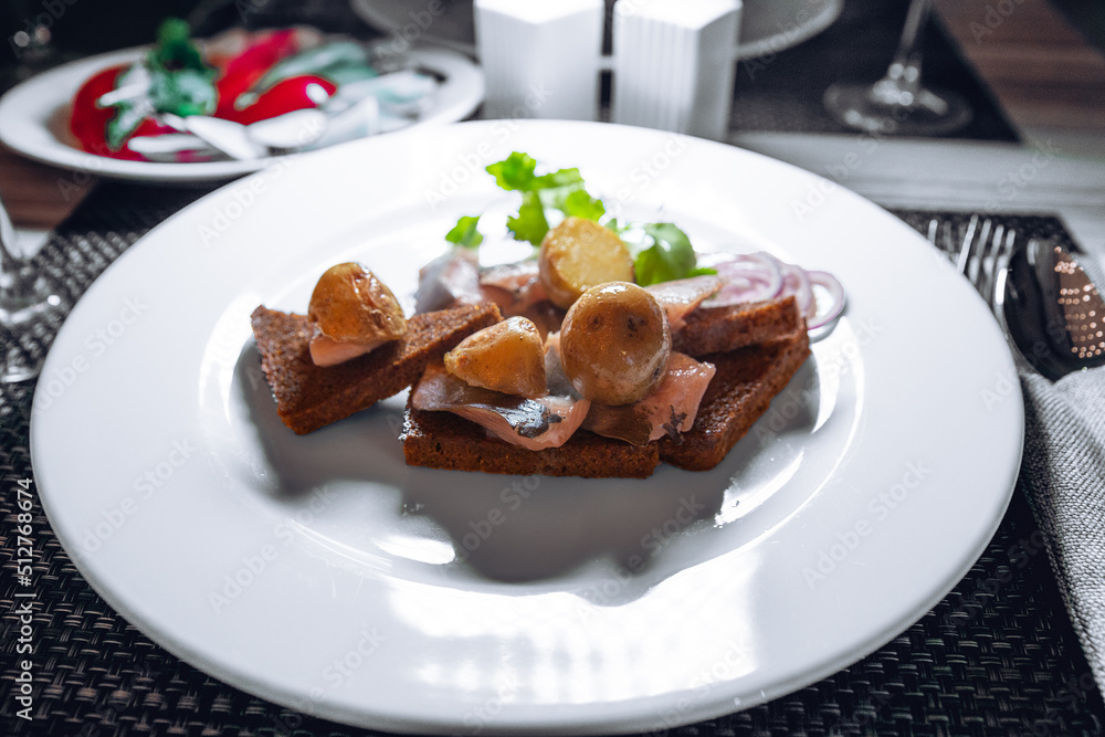 Boiled potatoes and pieces of salted herring on toast with onion rings and parsley Boiled potatoes and pieces of salted herring on toast with onion rings and parsley
