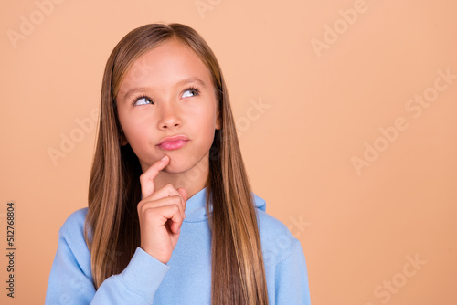 Portrait of cute minded pupil finger touch chin look interested empty space isolated on beige color background