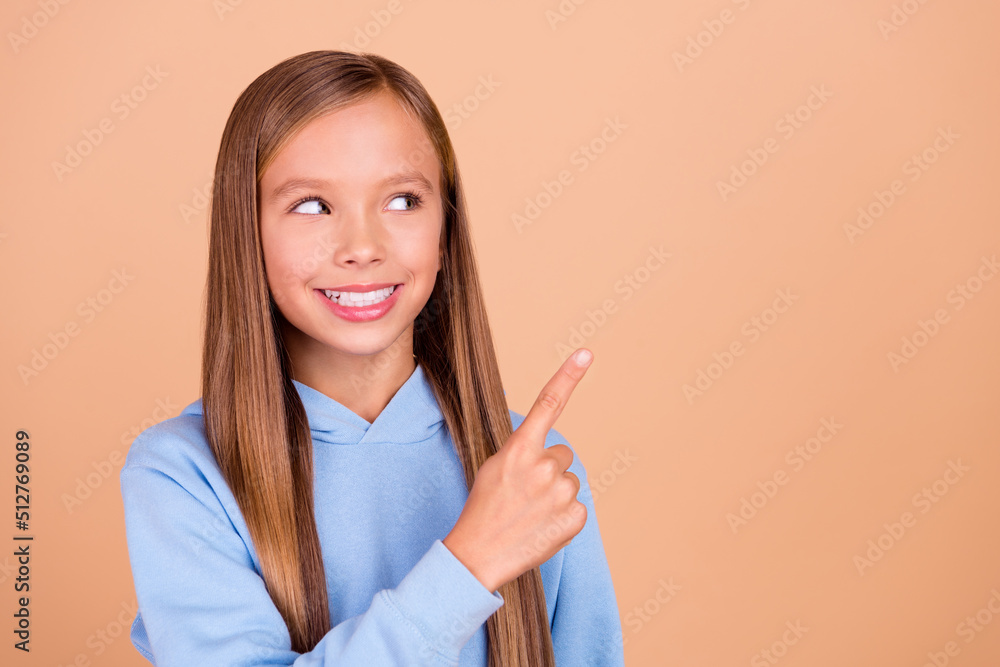 Portrait of cheerful nice pupil look indicate finger empty space isolated on beige color background Portrait of cheerful nice pupil look indicate finger empty space isolated on beige color background