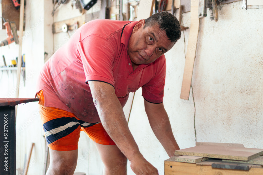 Portrait of carpenter standing by timber stack in workshop Portrait of carpenter standing by timber stack in workshop