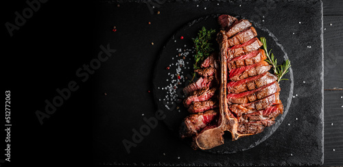 Dry Aged Barbecue Porterhouse Steak T-bone beef steak sliced with large fillet piece with herbs and salt. American meat restaurant