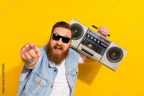 Photo of excited cool man wear jeans waistcoat arm dark eyewear listening boom box pointing you isolated yellow color background