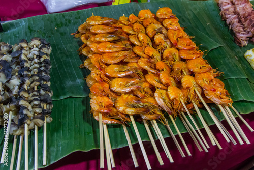 Street foods at walking street(Chai Khong Road) in Chiang Khan,Loei,Northeastern Thailand.-grilled shellfish skewers and grilled shrimp skewers.