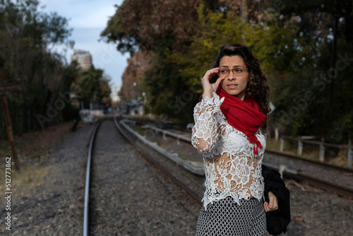 Young Latin American businesswoman walks across railroad tracks