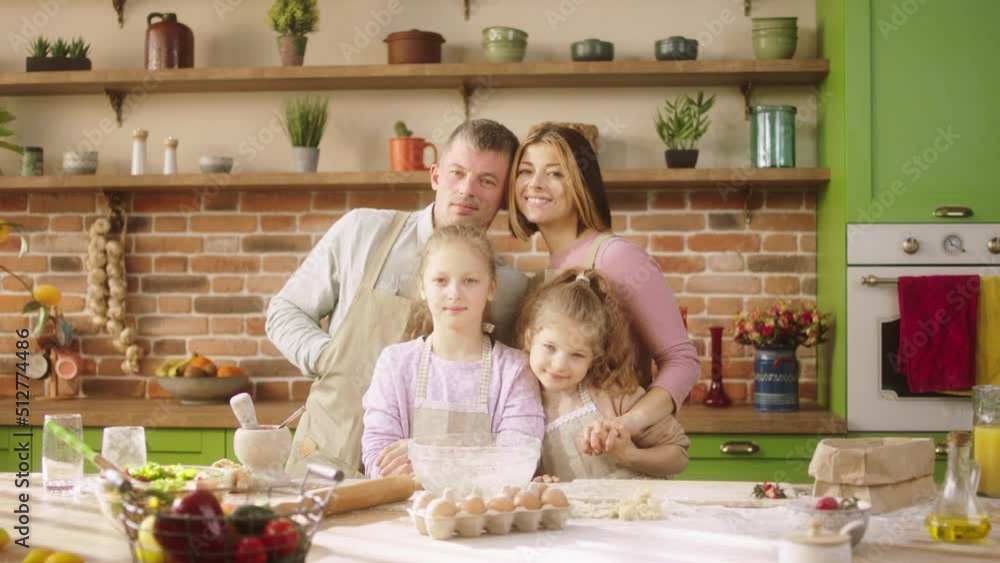 Portrait of a beautiful family members very charismatic posing at the home in the kitchen they looking straight to the camera and smiling large Portrait of a beautiful family members very charismatic posing at the home in the kitchen they looking straight to the camera and smiling large