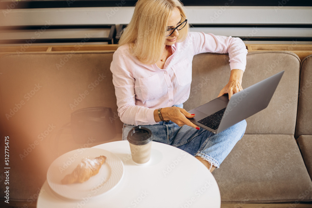 Woman working on laptop in a cafe and eating croissant Woman working on laptop in a cafe and eating croissant