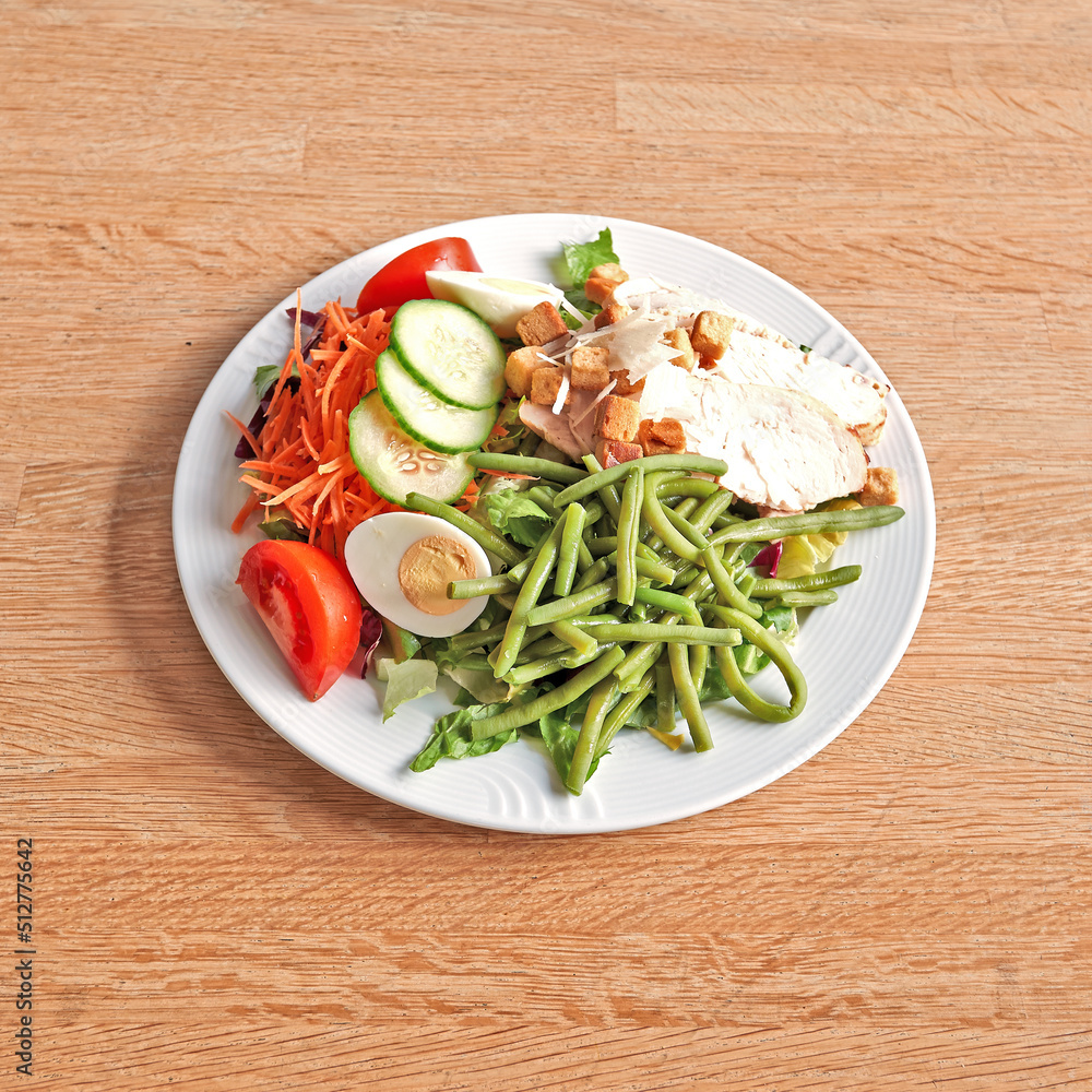 Plate with a Caesar salad on wooden table Plate with a Caesar salad on wooden table