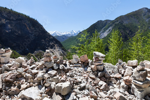 Stone pyramids of tourists on mountain pass Nuhu above channel of the Black Irkut river in mountain gorge on summer day. Road Mondy-Orlik, Buryatia. Beautiful mountain landscape. Natural background