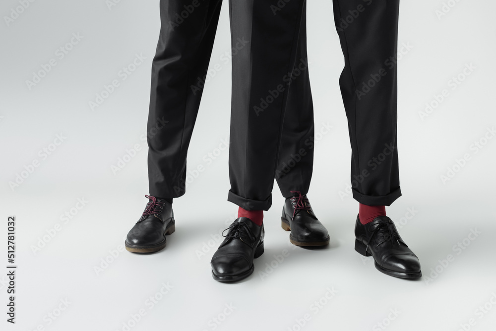 Cropped view of gay couple in shoes standing on grey background. Cropped view of gay couple in shoes standing on grey background.