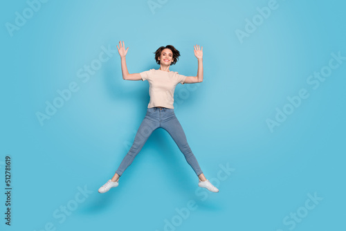 Fototapeta Naklejka Na Ścianę i Meble -  Full length photo of charming funny lady dressed beige t-shirt jumping up empty space isolated blue color background