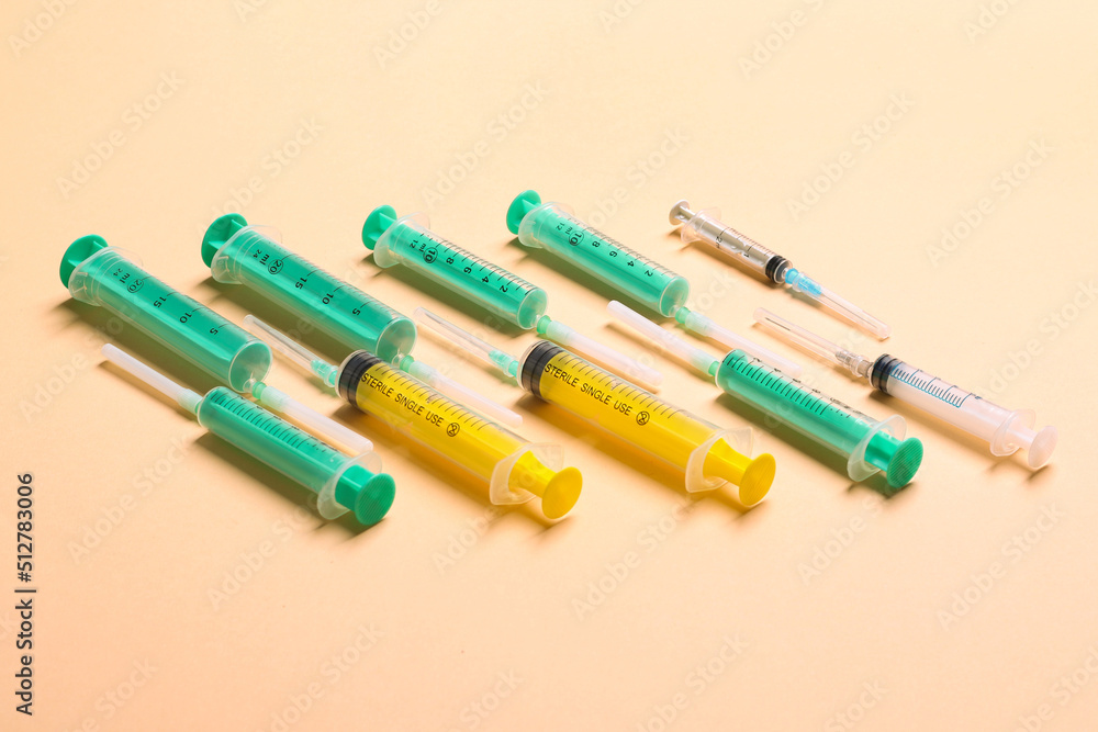 Top view of different syringes at orange background. Medical injection concept with copy space Top view of different syringes at orange background. Medical injection concept with copy space