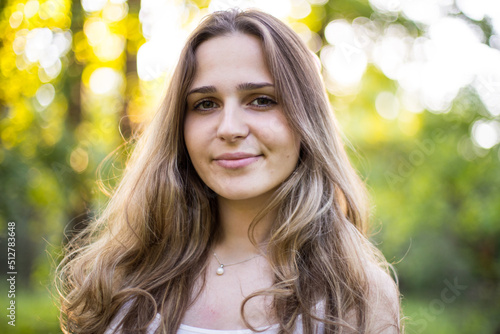Beautiful young Russian girl dressed in a white dress, walks through the forest among the oaks in the rays of the sunset