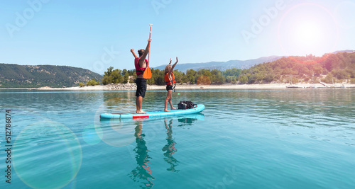 father and boy stand up  paddling on river or lake photo