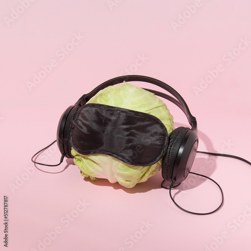 Cabbage head with eyemask and earphones on pastel background. Out of reality funny concept. Human head representation concept. photo