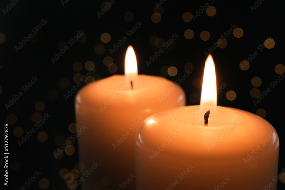Wax candles burning on black background with blurred lights, closeup. Bokeh effect Wax candles burning on black background with blurred lights, closeup. Bokeh effect