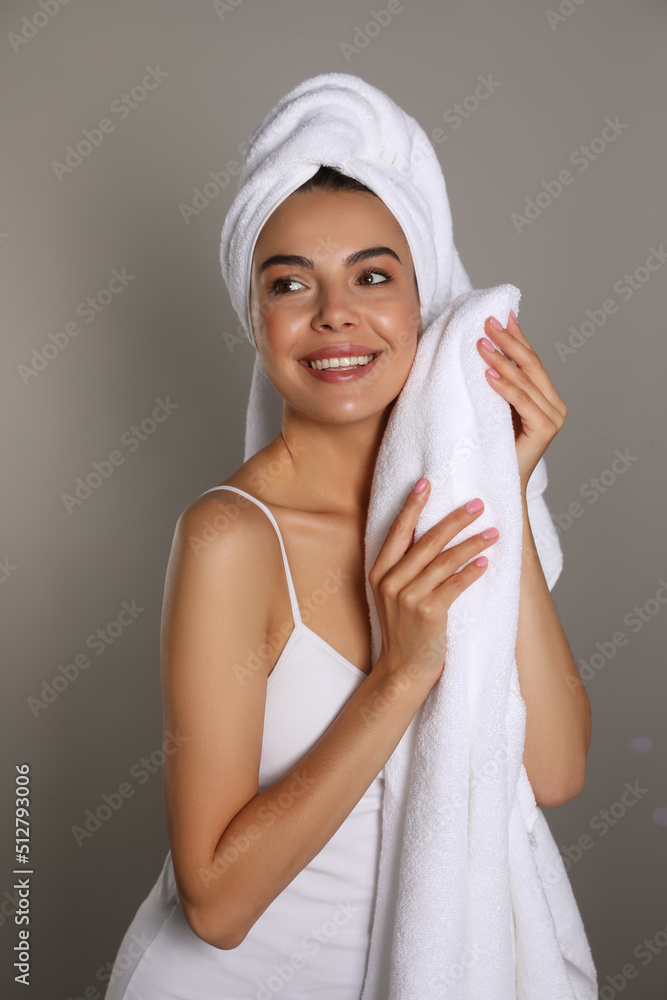 Beautiful young woman with towels on grey background Beautiful young woman with towels on grey background