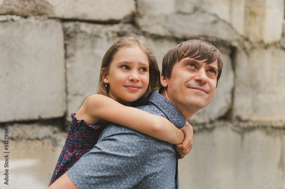 man dad having quality time with their kid daughter girl nine year old on his back. happy father playing with child. real life authentic day-to-day fatherhood moments. fatherly love care and affection