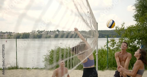 Friends in motion playing voleyball at lakeside