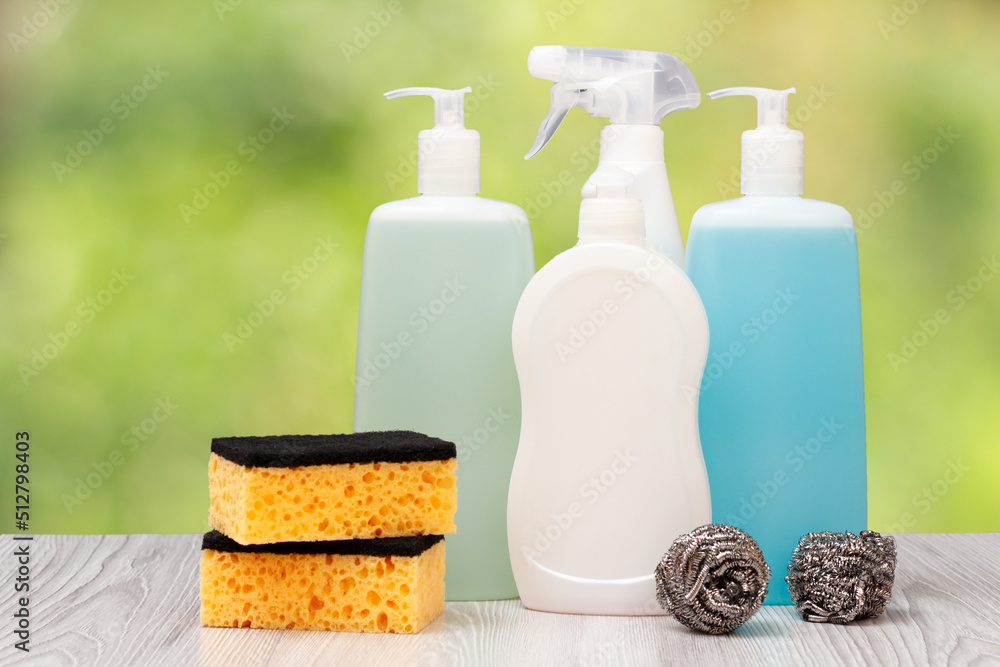 Bottles of dishwashing liquid and various sponges on natural background. Bottles of dishwashing liquid and various sponges on natural background.