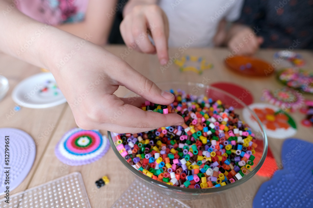 closeup of children's hands creating perler bead patterns, make crafts