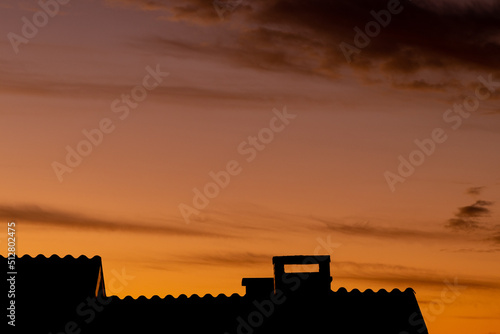 sunset in the city with silhouette of house and chimney