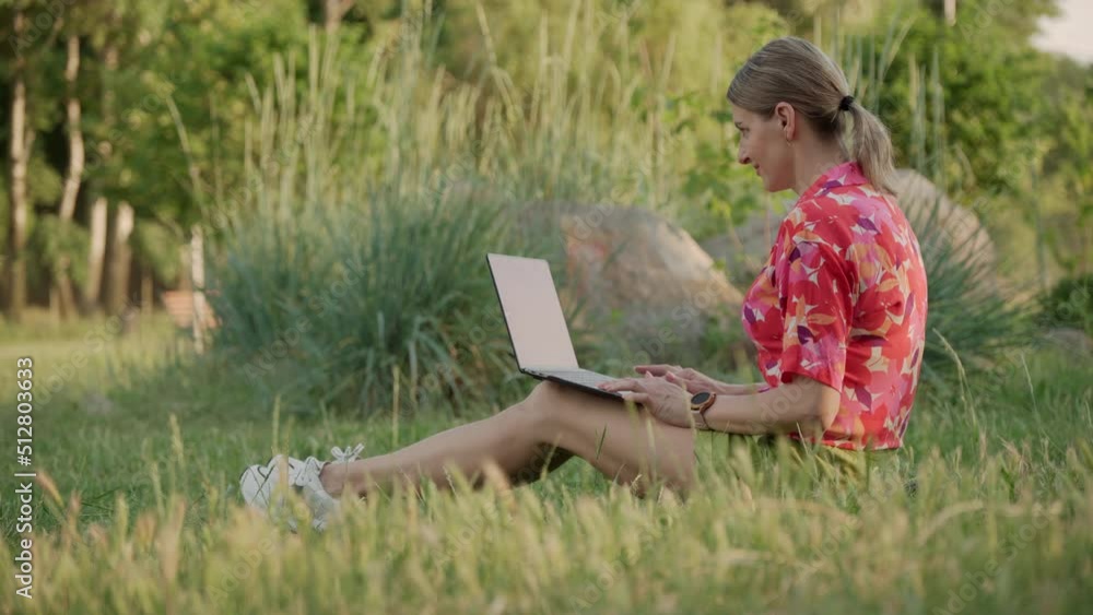 A middle-aged woman works using her laptop in a public park. She types and thinks. High quality 4k footage A middle-aged woman works using her laptop in a public park. She types and thinks. High quality 4k footage