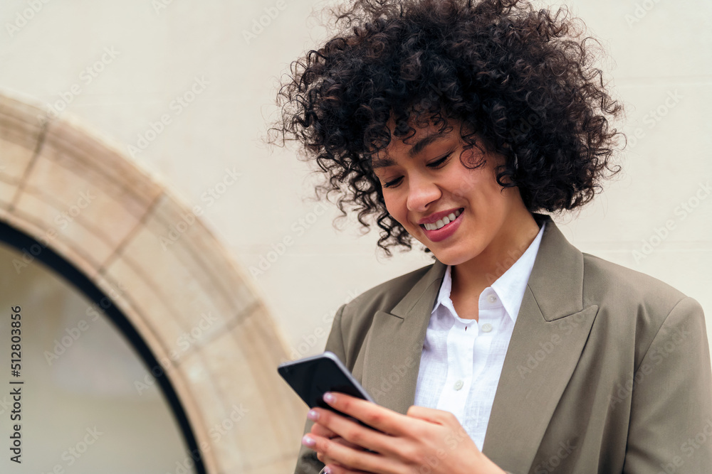portrait of a young woman with curly hair smiling happy typing a message with her mobile phone, concept of youth and technology, copy space for text portrait of a young woman with curly hair smiling happy typing a message with her mobile phone, concept of youth and technology, copy space for text