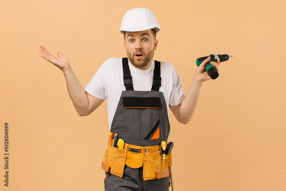 Positive male repairman at home holding a screwdriver and showing what he does not know on a beige background