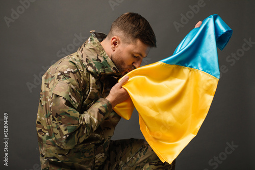 Portrait of a courageous Ukrainian military man kissing the flag of Ukraine, the concept of freedom photo