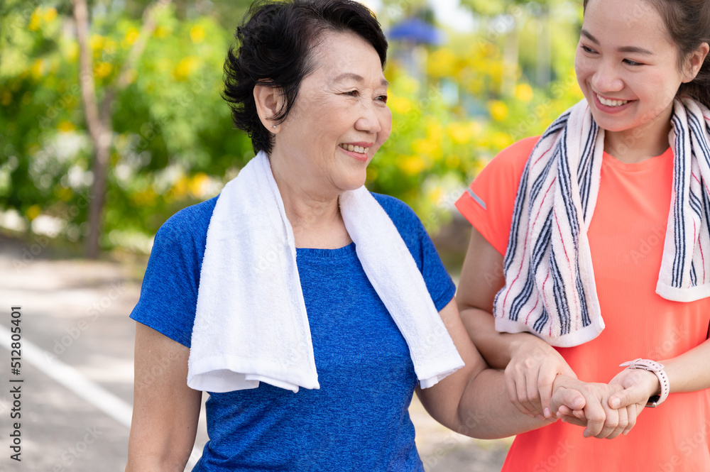 Asian senior mother and teenager daughter holding hands with exercise walking at park Asian senior mother and teenager daughter holding hands with exercise walking at park