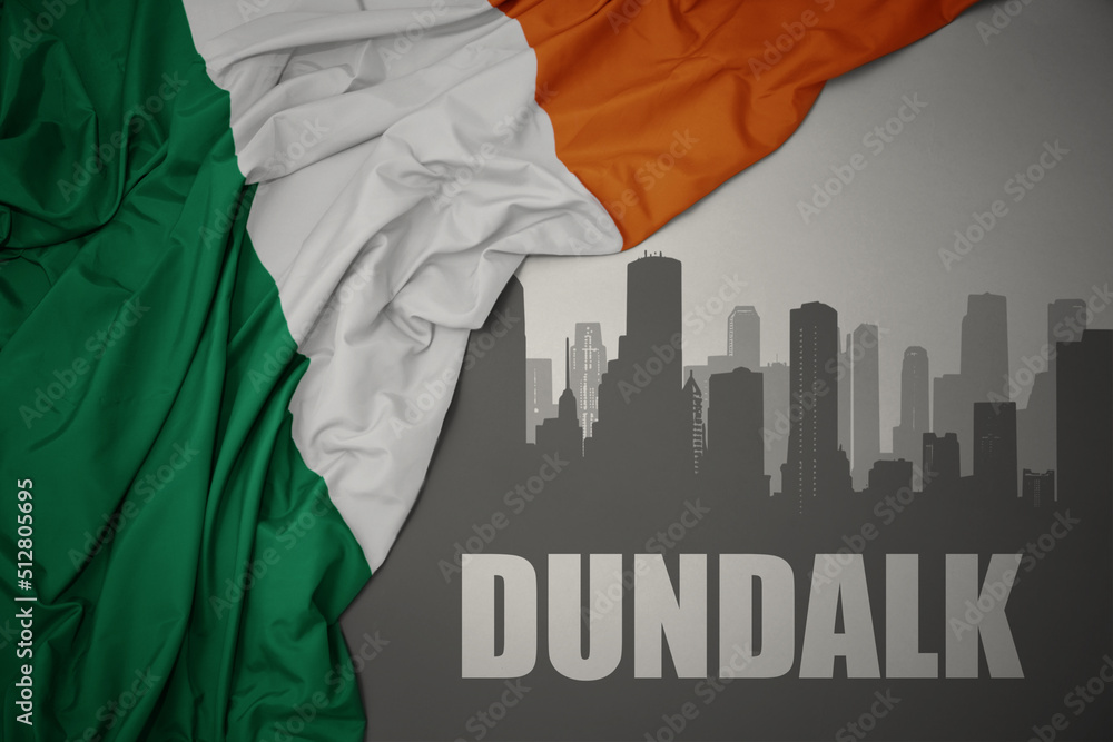abstract silhouette of the city with text Dundalk near waving national flag of ireland on a gray background.