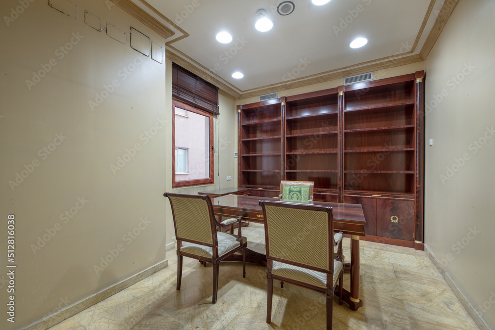 Fototapeta premium Office with vintage wooden table with matching bookshelf and beige marble floors