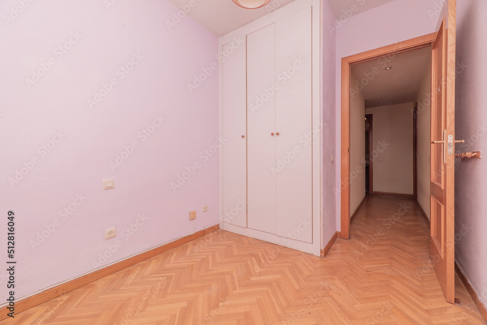 Empty bedroom with white wooden built-in wardrobe and French oak parquet floors placed in herringbone Empty bedroom with white wooden built-in wardrobe and French oak parquet floors placed in herringbone