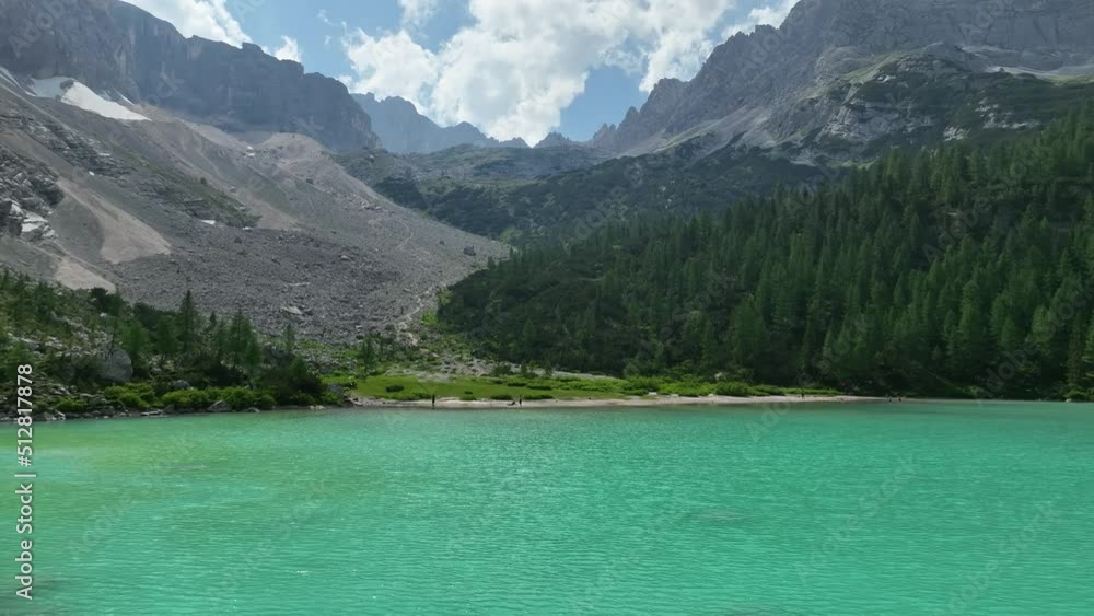 Hikers and travelers enjoying the turquoise Lago di Sorapiss (mountain lake) view as they have a mountain walk in the Dolomites Mountains, Italy. Active people in nature concept. Hikers and travelers enjoying the turquoise Lago di Sorapiss (mountain lake) view as they have a mountain walk in the Dolomites Mountains, Italy. Active people in nature concept.