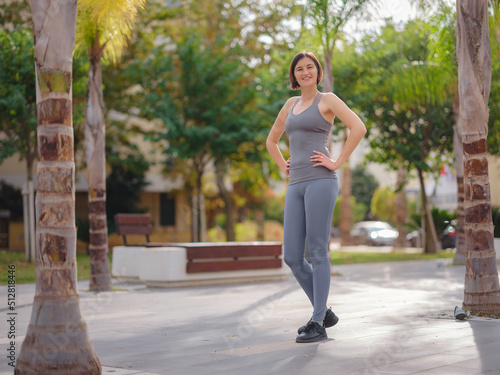 outdoor sports, workout and wellness concept. asian young strong, confident woman in sportive clothes in green park warming up before jogging outdoors, leg stretching before running.