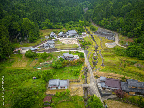 Aerial view of houses and shrine in small community by forest and mountains