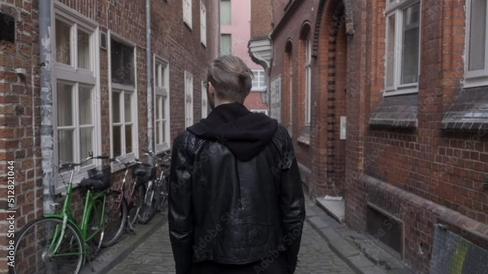 Young Man Walking Through Alley in Lüneburg Oldtown with Bicycles Young Man Walking Through Alley in Lüneburg Oldtown with Bicycles