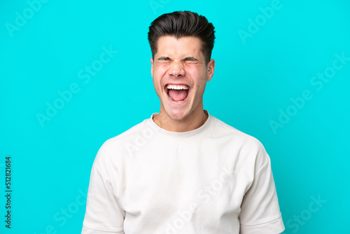 Young handsome caucasian man isolated on blue bakcground shouting to the front with mouth wide open