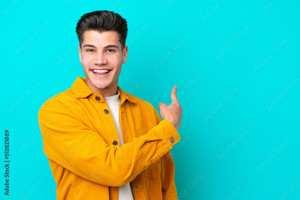 Young handsome caucasian man isolated on blue bakcground pointing back Young handsome caucasian man isolated on blue bakcground pointing back