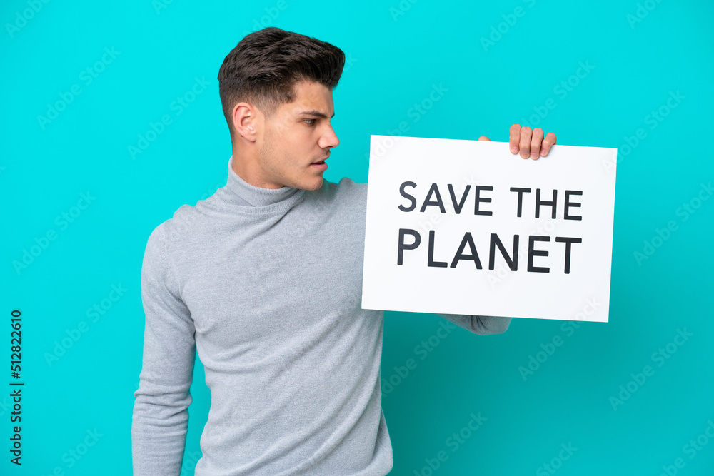 Young handsome caucasian man isolated on blue bakcground holding a placard with text Save the Planet Young handsome caucasian man isolated on blue bakcground holding a placard with text Save the Planet