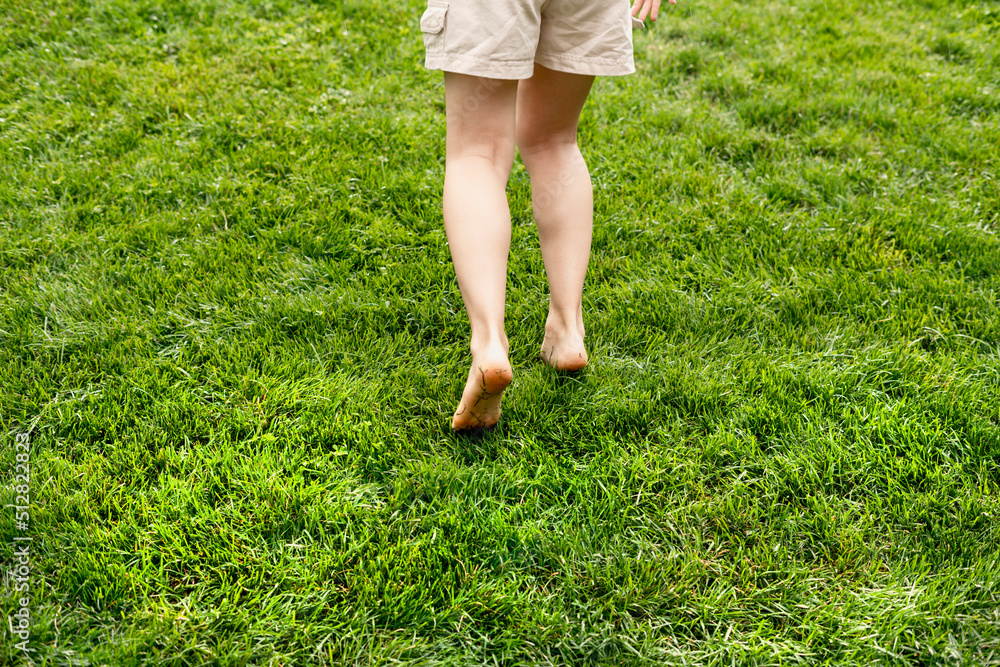 Woman feet barefoot closeup walking on green grass lawn Summer concept enjoying nature feeling Woman feet barefoot closeup walking on green grass lawn Summer concept enjoying nature feeling