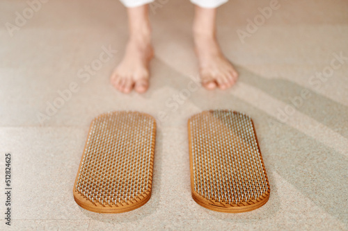 Cropped of woman standing near wooden sadhu board with nails before practice, yoga desk for regular practice, relieves nervous stress, tiredness, emotional over excitation photo