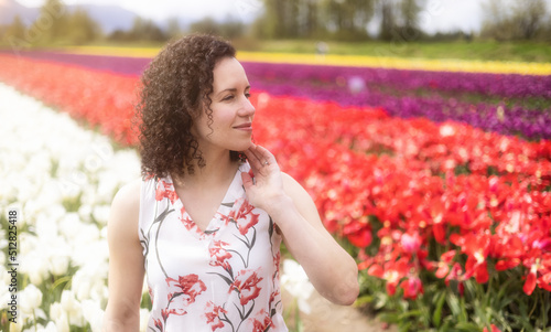 Caucasian Adult Woman looking at fresh Tulip Flowers in a field. Spring Season.