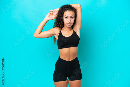 Young Arab woman isolated on blue background stretching
