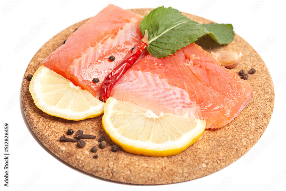 Pieces of lightly salted trout with herbs, spices and lemon on a wooden board Pieces of lightly salted trout with herbs, spices and lemon on a wooden board