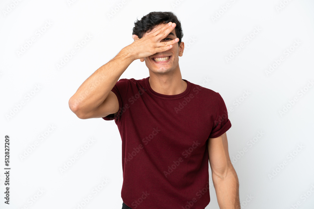 Young Argentinian man isolated on white background covering eyes by hands and smiling Young Argentinian man isolated on white background covering eyes by hands and smiling