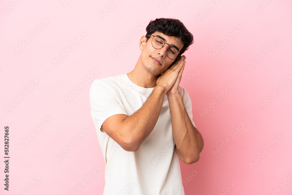 Young Argentinian man isolated on pink background making sleep gesture in dorable expression Young Argentinian man isolated on pink background making sleep gesture in dorable expression