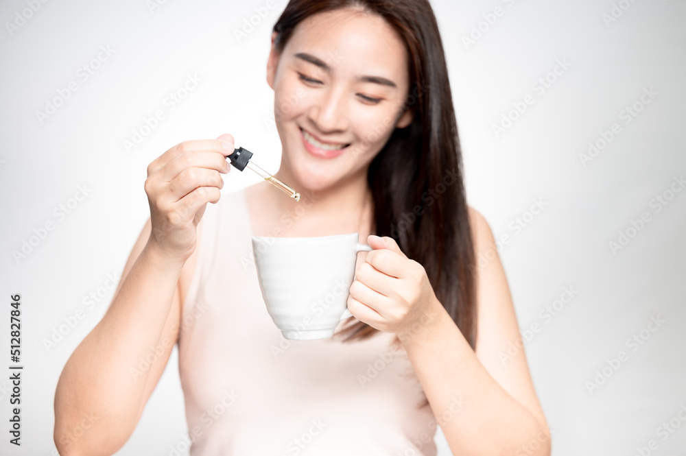 Woman dripping cbd oil inside tea cup, cofee cup - Alternative medicine, vitamins and supplements concept - Focus on dropper Woman dripping cbd oil inside tea cup, cofee cup - Alternative medicine, vitamins and supplements concept - Focus on dropper
